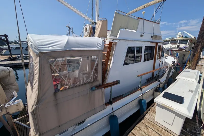 Slide: The Image of 1987 Island Gypsy 32 boat docked at marina with covered deck and wooden railings. - 33