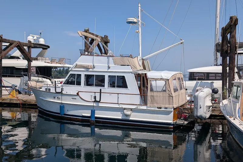 Slide: The Image of 1987 Island Gypsy 32 yacht docked at marina, featuring classic design and beige canopy. - 36