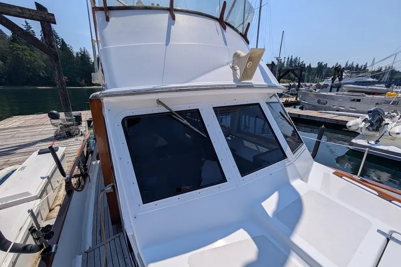 Slide: The Image of 1987 Island Gypsy 32 boat docked at a marina, featuring a white cabin and clear windows. - 4