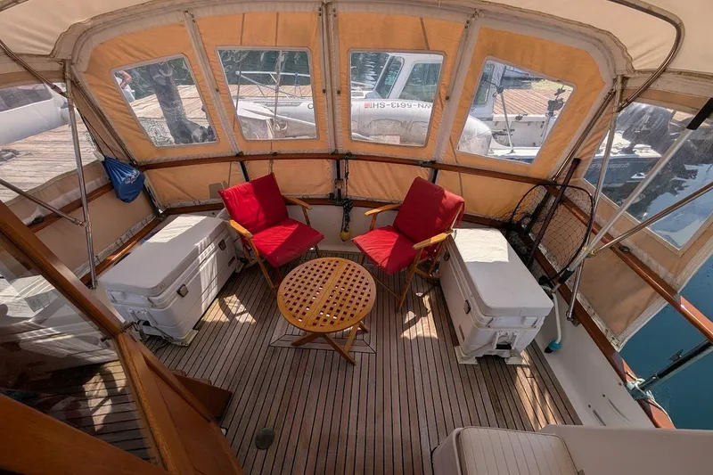 Slide: The Image of 1987 Island Gypsy 32 boat interior with red chairs, wooden table, and coolers. - 20