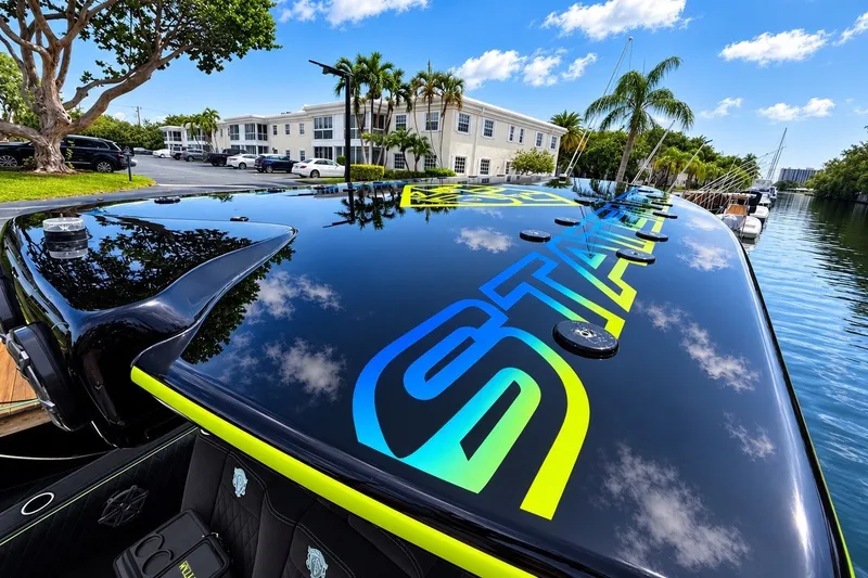 Slide: The Image of Sleek 2017 Statement 380 Open boat with vibrant graphics, docked near palm trees and waterfront buildings. - 41