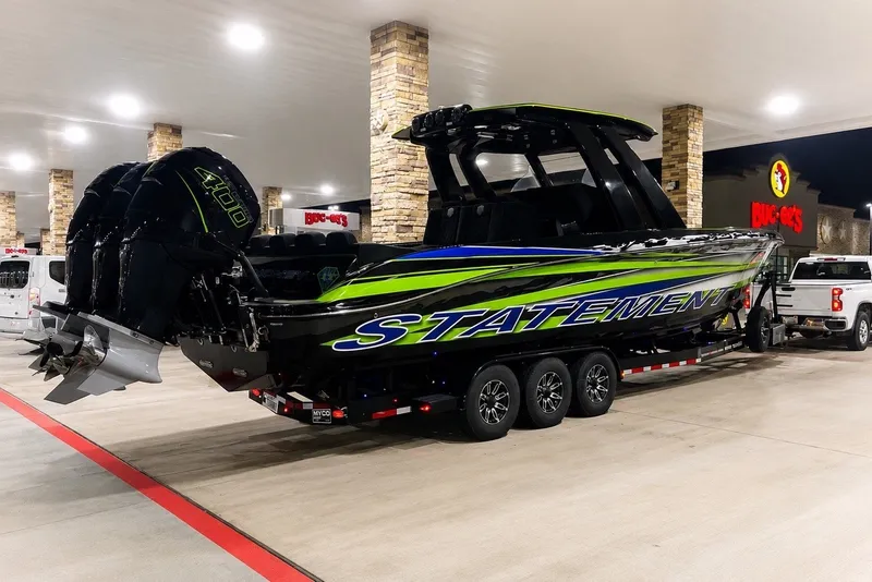 Slide: The Image of 2017 Statement 380 Open boat on trailer at gas station, featuring bold graphics and powerful engines. - 14