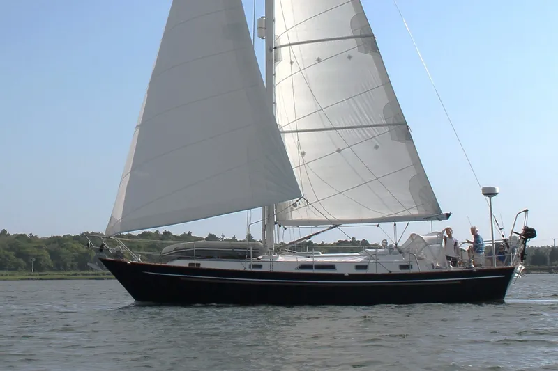 The Image of Sailing yacht Passport 40 from 1986 on calm waters, with lush greenery in the background. - 0