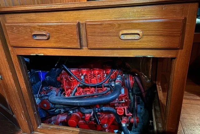 Slide: The Image of Engine compartment of a 1986 Passport 40 sailboat, featuring a red engine beneath wooden cabinetry. - 16