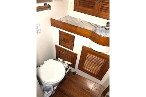 Slide: The Image of 1983 Passport 40 yacht bathroom with wooden cabinets and white toilet. - 15