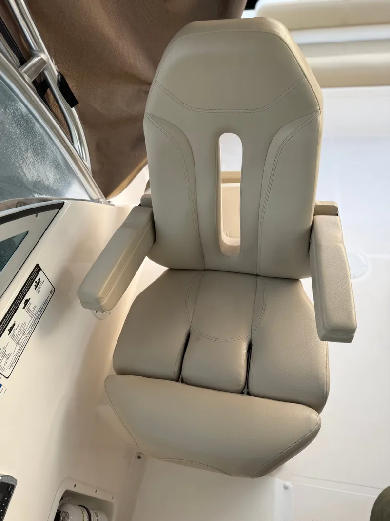 Slide: The Image of A beige captain's chair with armrests on a boat, surrounded by a white surface. - 12