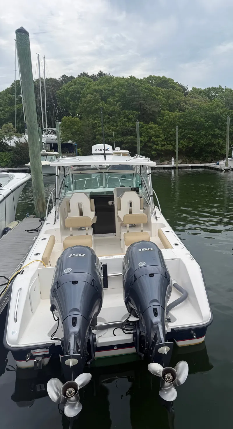 Slide: The Image of A 2016 Pursuit OS 255 Offshore boat docked. It features twin outboard engines. - 2