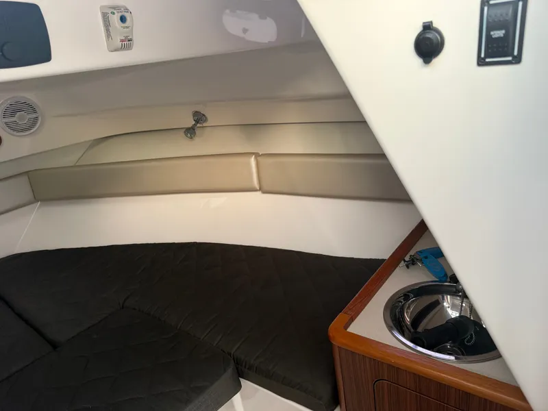 Slide: The Image of Interior of a 2016 Pursuit OS 255 Offshore with cushioned seating and a small sink. - 16
