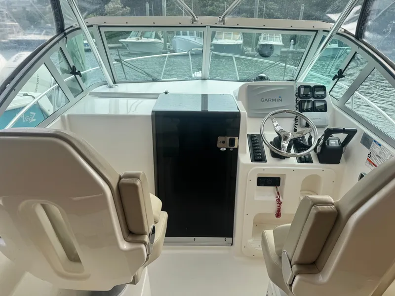 Slide: The Image of The cockpit of a 2016 Pursuit OS 255 Offshore with two seats and a helm station. - 7