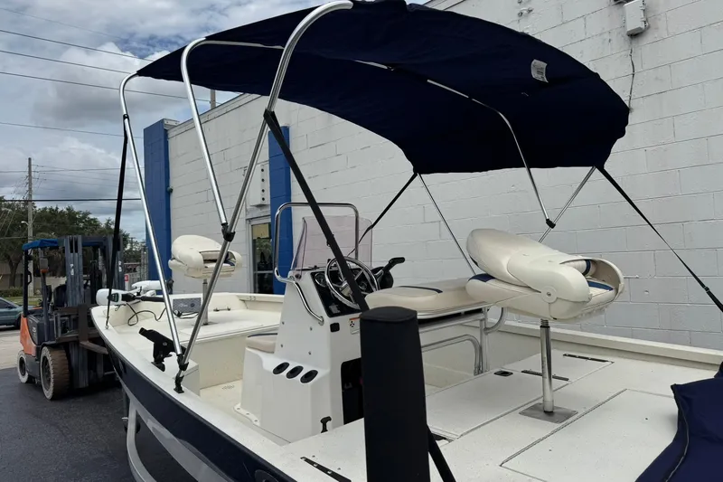 Slide: The Image of 2018 G3 Bay 18 DLX boat with canopy, parked near a building. - 11