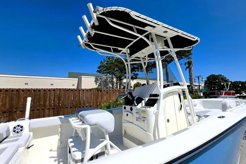 Slide: The Image of 2026 Mako 214 Center Console boat with T-top and seating, under clear blue sky. - 19