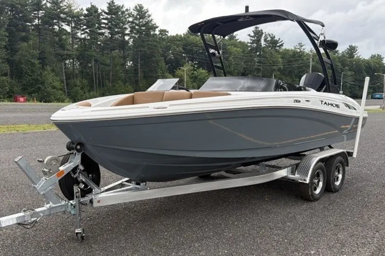 Slide: The Image of 2026 Tahoe 210 S boat on trailer, parked outdoors with forest background. - 1
