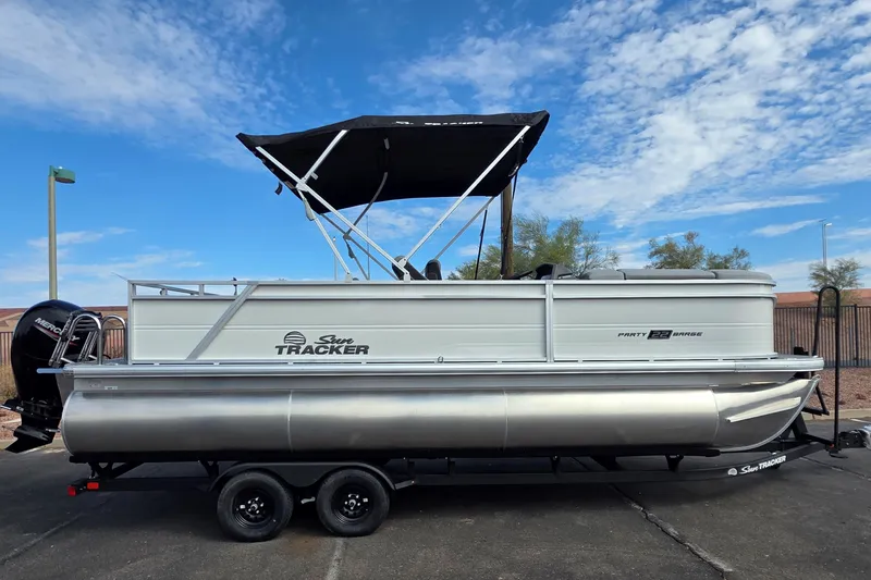 The Image of 2026 Sun Tracker Party Barge 22 RF DLX pontoon boat on trailer under blue sky. - 0