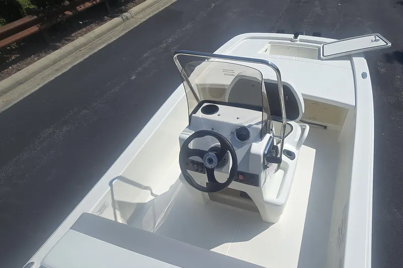 Slide: The Image of 2026 Mako Pro Skiff 13 CC boat with center console and steering wheel, parked on pavement. - 3