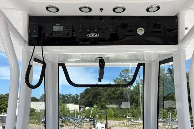 Slide: The Image of 2026 Sea Hunt BX25FS boat console with controls and radio, set against a clear sky. - 11