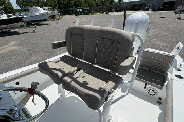 Slide: The Image of 2026 Sea Hunt BX25FS boat interior with cushioned seating and steering wheel in a marina setting. - 7