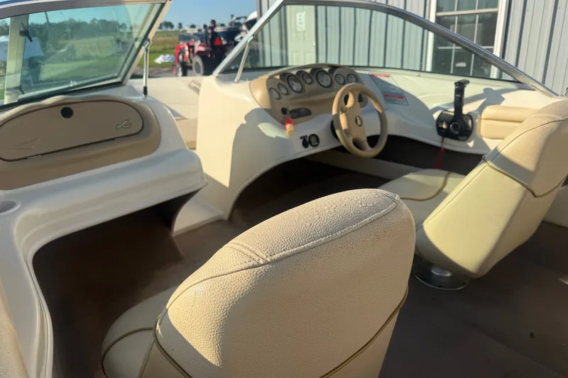 Slide: The Image of Interior of a 2000 Searay 180 boat, featuring beige seating and dashboard controls. - 11