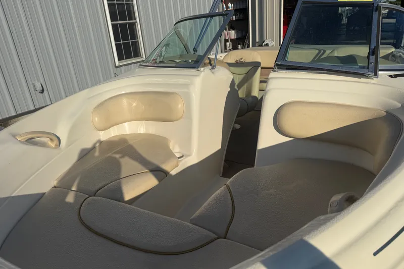 Slide: The Image of 2000 Searay 180 boat interior with beige seating and windshield, parked near a building. - 9