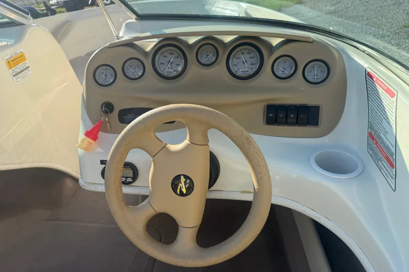 Slide: The Image of Steering wheel and dashboard of a 2000 Searay 180 boat, featuring gauges and controls. - 12
