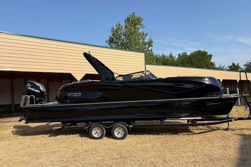 Slide: The Image of Black 2019 SunCatcher Amara boat on trailer, parked outdoors with Suzuki engine. - 27