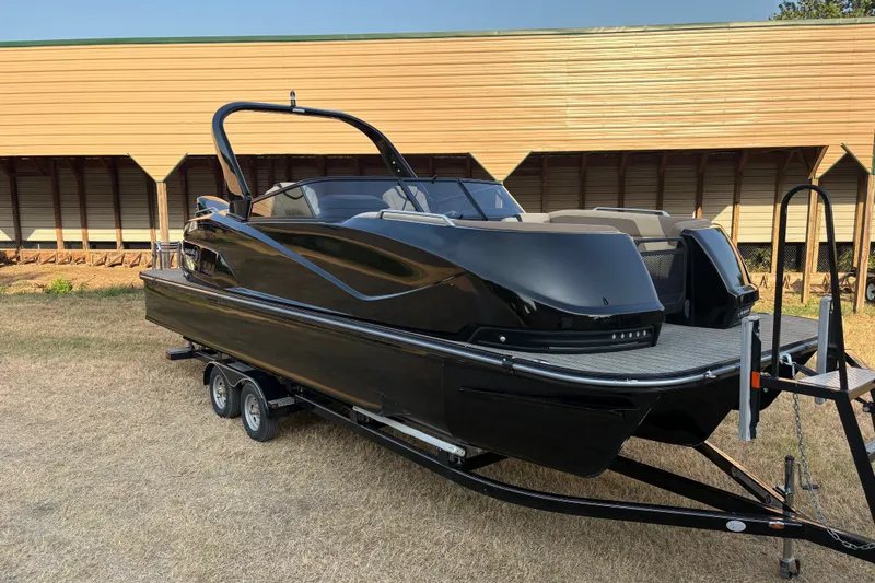 The Image of 2019 SunCatcher Amara boat on trailer, sleek black design, parked outdoors. - 1