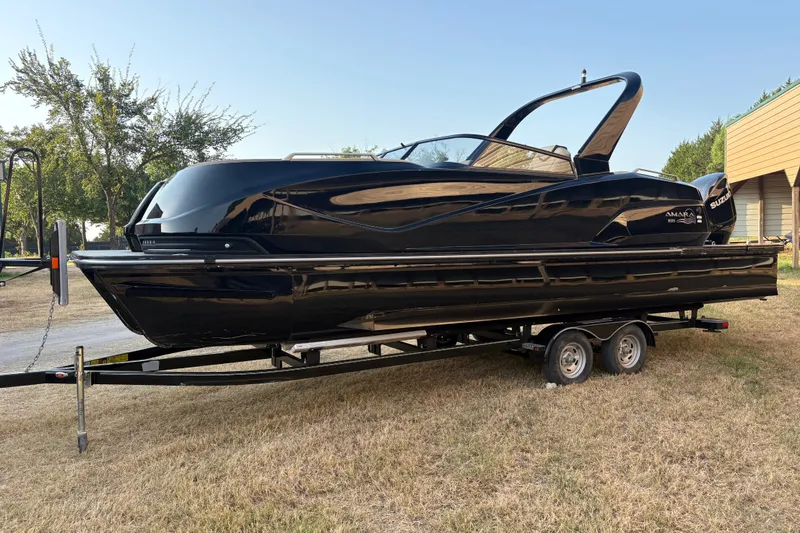 Slide: The Image of 2019 SunCatcher Amara boat on trailer, sleek black design, parked on grass. - 5