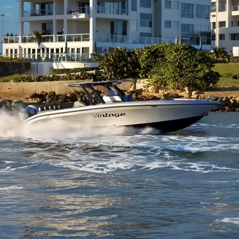 Slide: The Image of A 2021 Midnight Express 37 Open speeds across the water in front of modern buildings. - 0