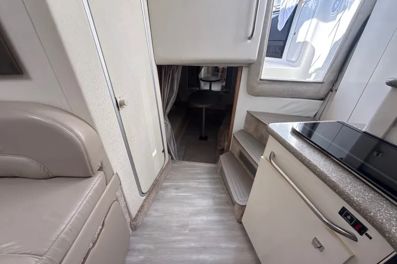 Slide: The Image of Interior of 1999 Maxum 3300 SCR boat, featuring compact kitchen and seating area. - 50