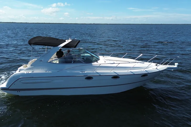 Slide: The Image of 1999 Maxum 3300 SCR boat cruising on open water under clear skies. - 3