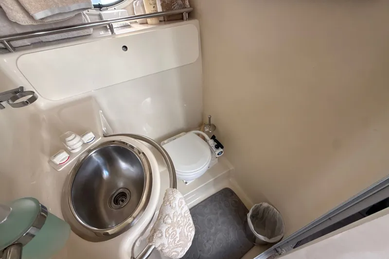 Slide: The Image of 1999 Maxum 3300 SCR boat bathroom with sink, toilet, and storage shelves. - 49