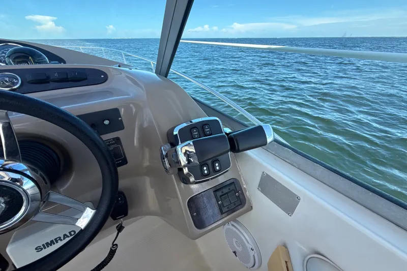 Slide: The Image of 1999 Maxum 3300 SCR boat helm with ocean view, featuring steering wheel and controls. - 24