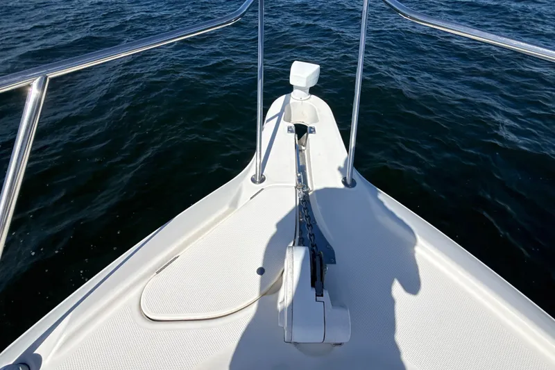 Slide: The Image of Bow view of 1999 Maxum 3300 SCR boat on water, featuring anchor and railing. - 59