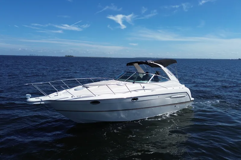 The Image of 1999 Maxum 3300 SCR boat cruising on open water under a clear blue sky. - 0