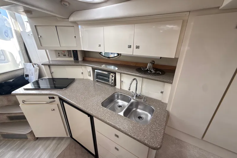 Slide: The Image of 1999 Maxum 3300 SCR yacht kitchen with dual sinks, stovetop, and ample cabinetry. - 44