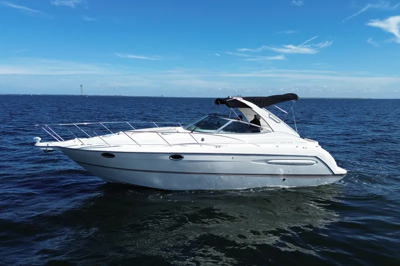 Slide: The Image of 1999 Maxum 3300 SCR yacht cruising on open water under clear blue skies. - 6