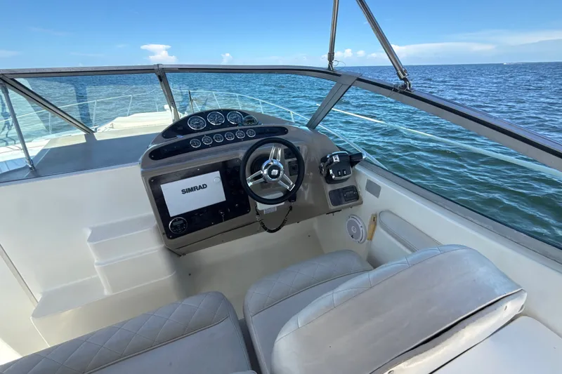 Slide: The Image of 1999 Maxum 3300 SCR boat cockpit with steering wheel and navigation system, overlooking the ocean. - 19