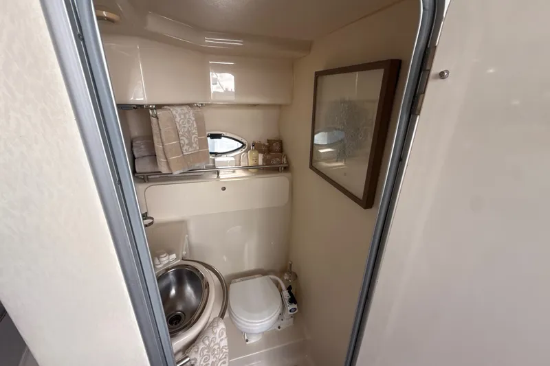 Slide: The Image of Compact bathroom in a 1999 Maxum 3300 SCR boat, featuring sink, toilet, and decorative elements. - 47