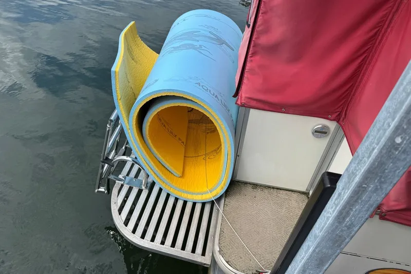Slide: The Image of 2008 Sun Tracker Party Hut 30 I/O with rolled aqua mat on deck by water. - 34