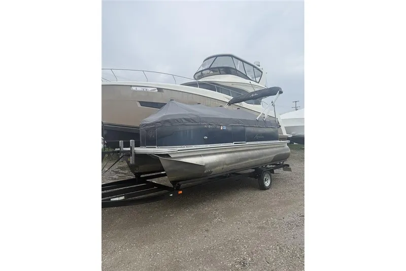 Slide: The Image of 2024 Avalon VLS Quad Lounge 19' pontoon boat on trailer, covered and parked outdoors. - 1