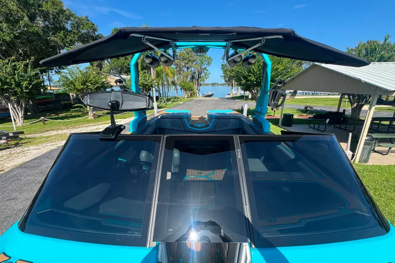 Slide: The Image of 2022 Nautique Super Air Nautique G23 boat with blue exterior, docked near a scenic waterfront. - 109