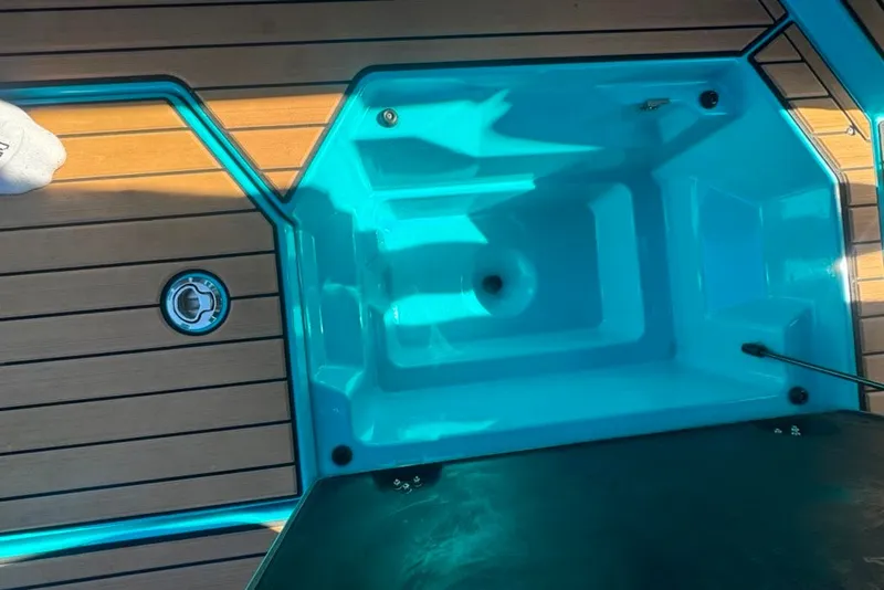 Slide: The Image of 2022 Nautique Super Air Nautique G23 boat interior with teal storage compartment and wooden deck. - 38