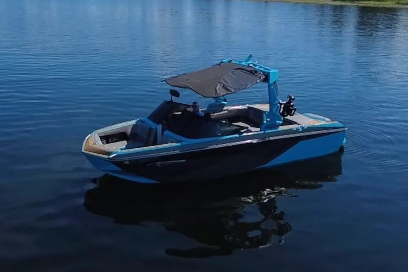 Slide: The Image of 2022 Nautique Super Air Nautique G23 boat on calm water, featuring sleek design and canopy. - 101