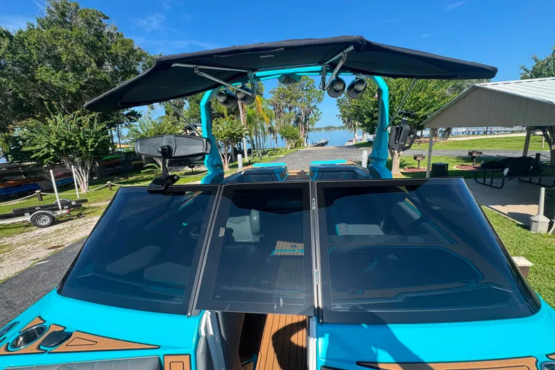 Slide: The Image of 2022 Nautique Super Air Nautique G23 boat with blue exterior, docked near a scenic lake. - 110