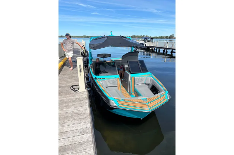 Slide: The Image of 2022 Nautique Super Air Nautique G23 docked, featuring vibrant teal and orange design. - 28