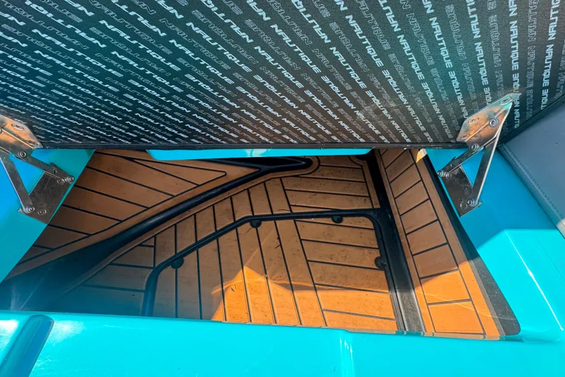 Slide: The Image of 2022 Nautique Super Air Nautique G23 storage compartment with teak flooring and Nautique branding. - 69