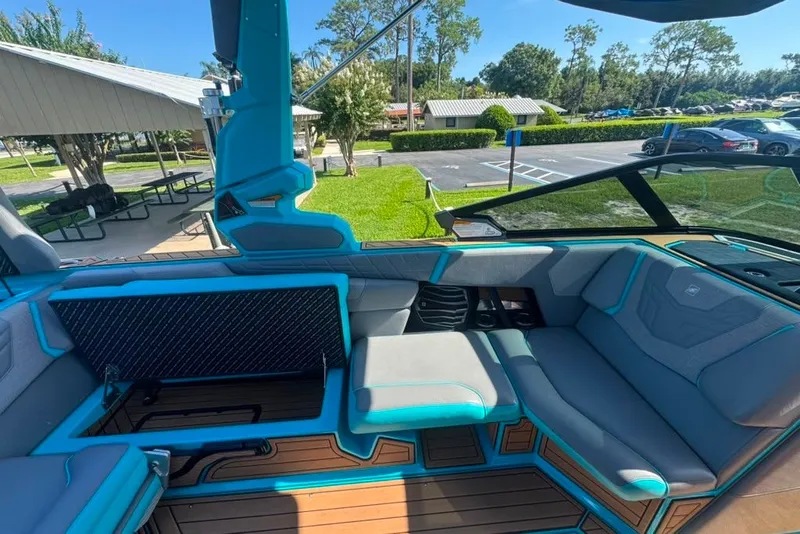 Slide: The Image of 2022 Nautique Super Air Nautique G23 interior with blue and gray seating, parked outdoors. - 99