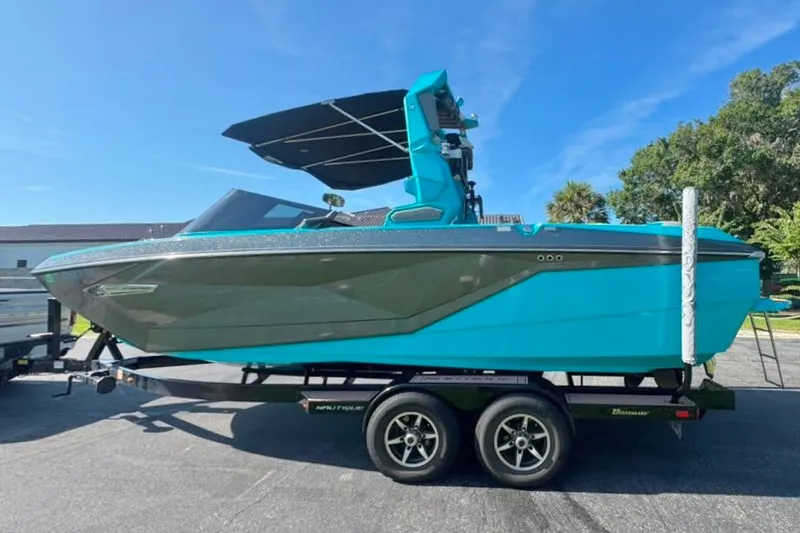 Slide: The Image of 2022 Nautique Super Air Nautique G23 boat on trailer, vibrant blue color, sunny day. - 12