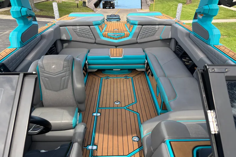 Slide: The Image of 2022 Nautique Super Air Nautique G23 interior with gray and teal seating, wooden flooring. - 27