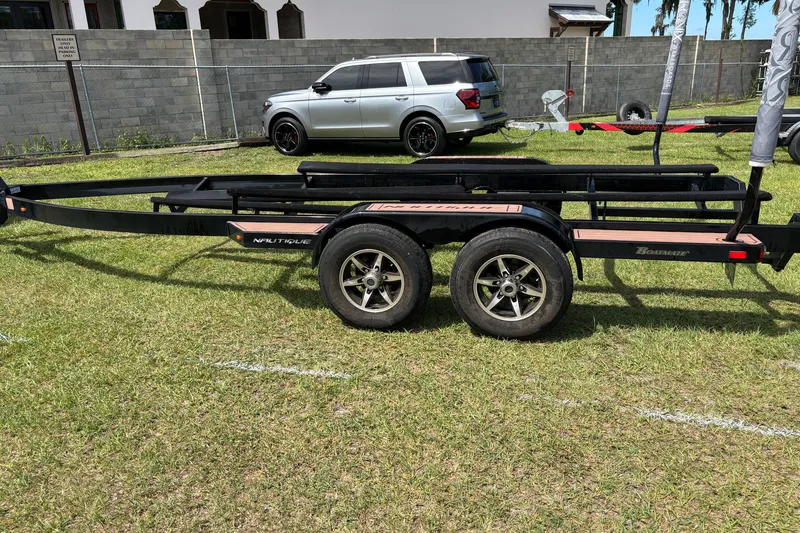Slide: The Image of Trailer for 2022 Nautique Super Air Nautique G23 on grass, with a parked SUV nearby. - 30