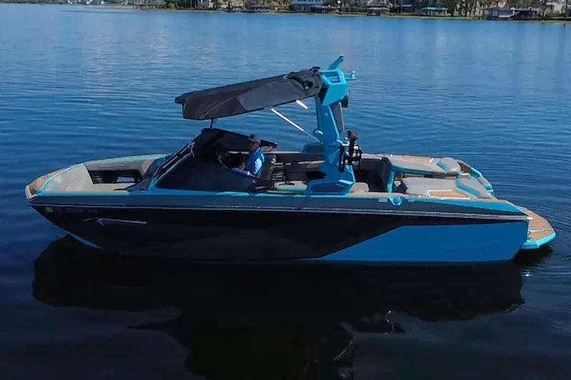 Slide: The Image of 2022 Nautique Super Air Nautique G23 boat on calm water, featuring sleek design and canopy. - 52